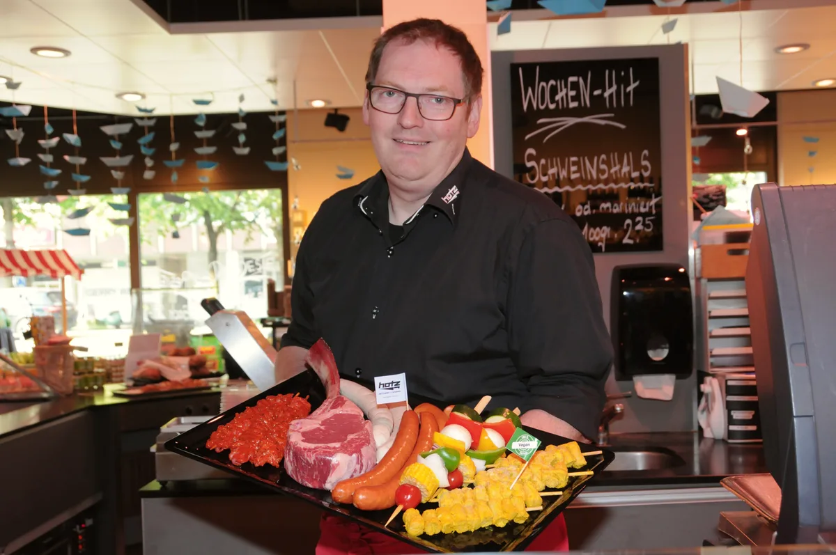 Man sieht den Metzger mit einer Grillplatte.